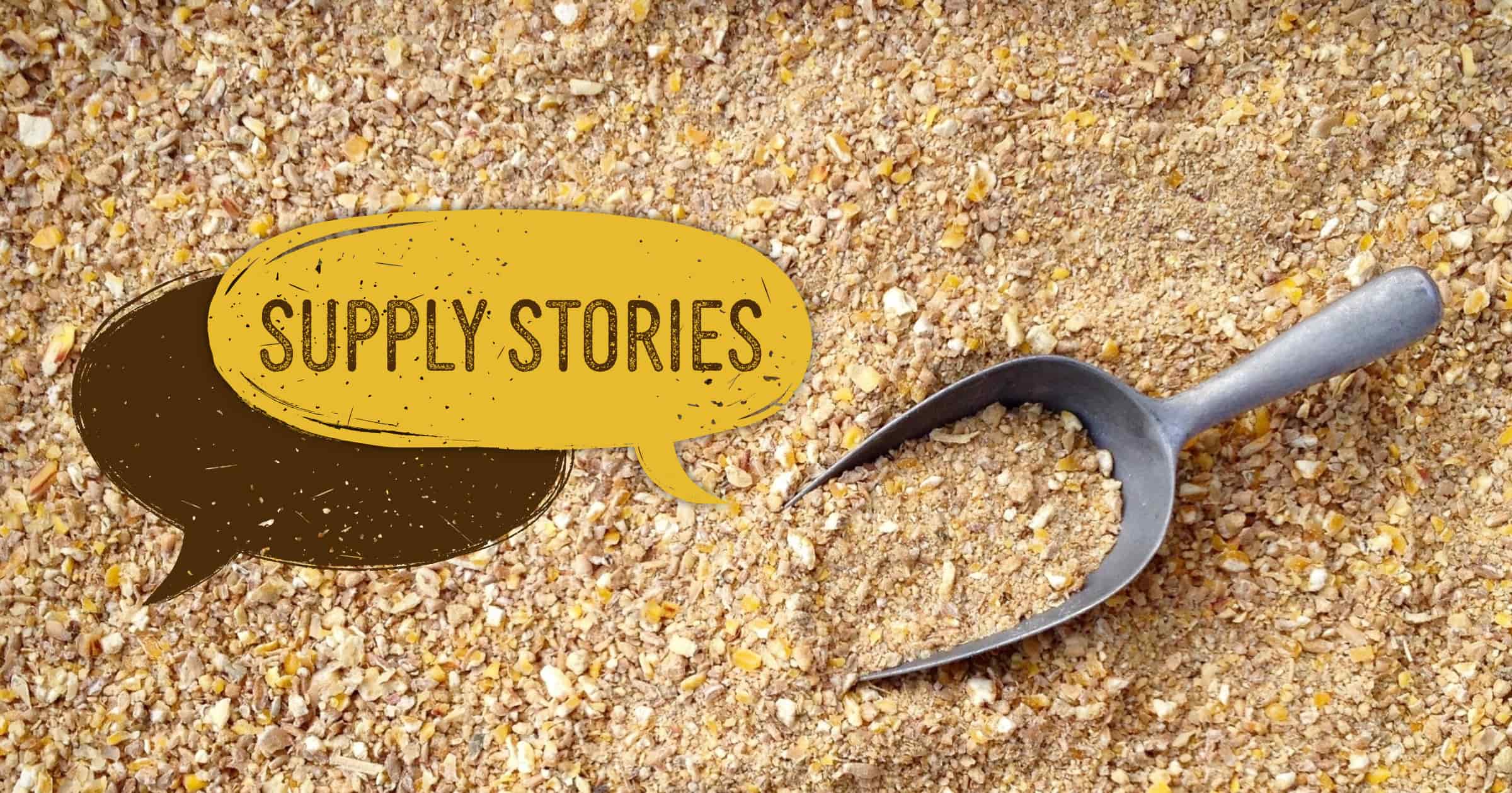 A large pile of ground-up corn feed with a metal scoop in the middle.